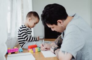 Épisode 2 – Impact des adultes et de l’environnement : risque ou protection pour l’enfant ? Père et enfant dessinant ensemble — présence protectrice et bienveillante